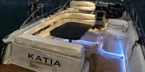 Stern lounge on board Katia at night with table set up for aperitif under blue under-glow